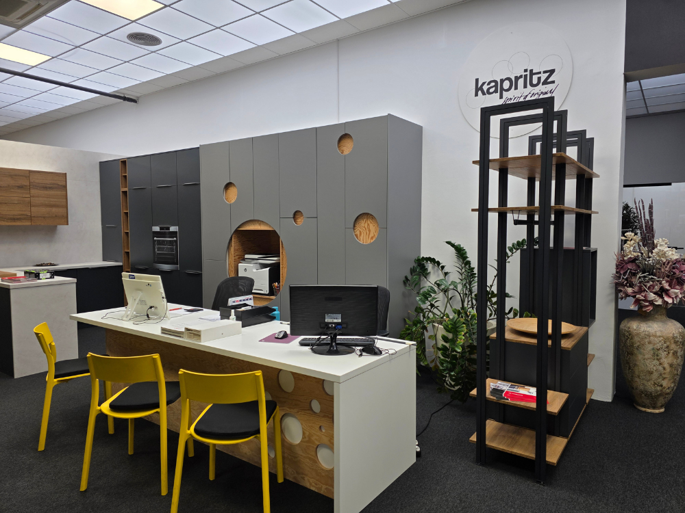 Moderný showroom s pracovným stolom, žltými stoličkami a vstavaným nábytkom s dizajnovými prvkami.